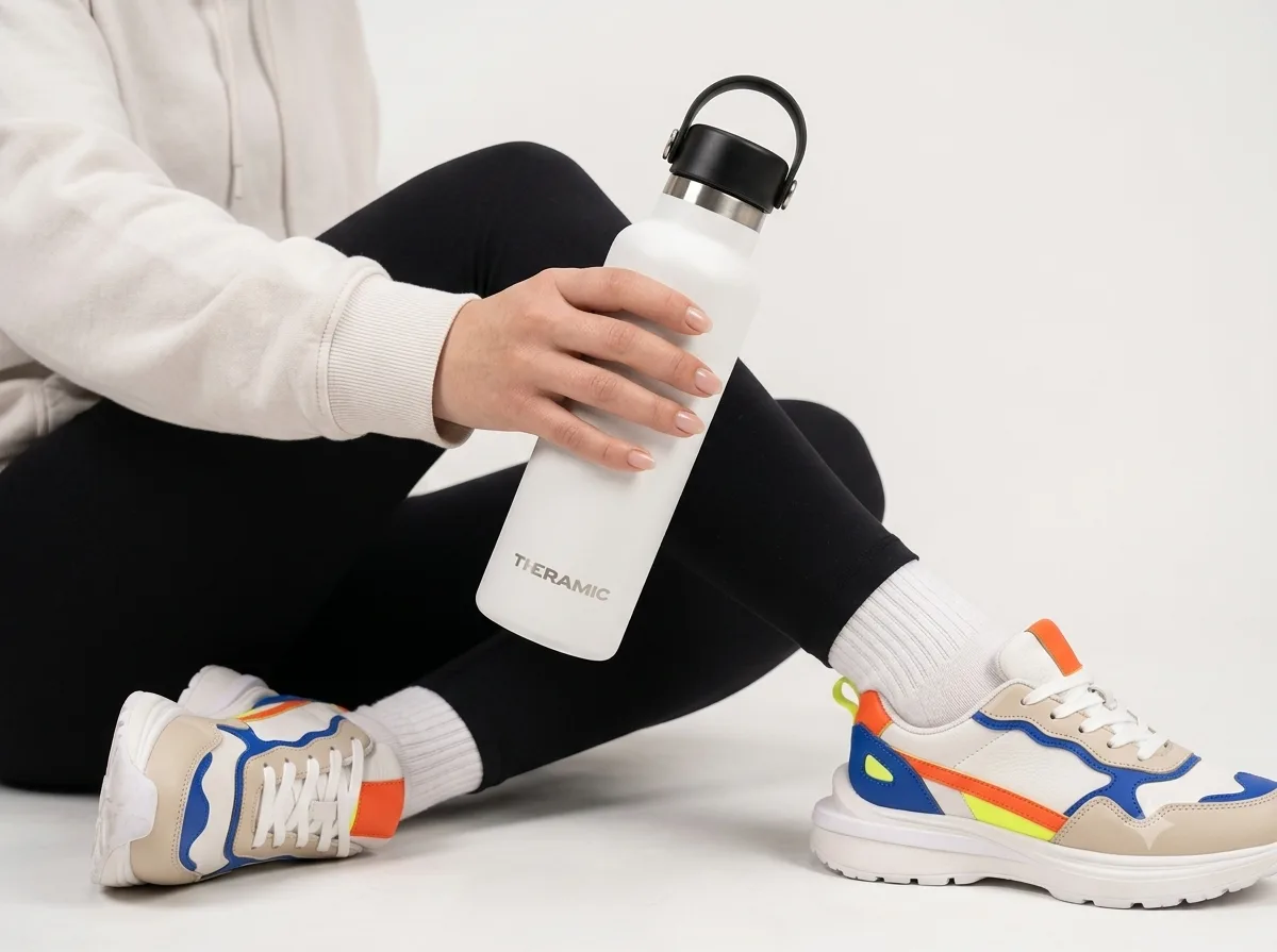 Botella térmica Theramic blanca sujeta con la mano después de entrenar